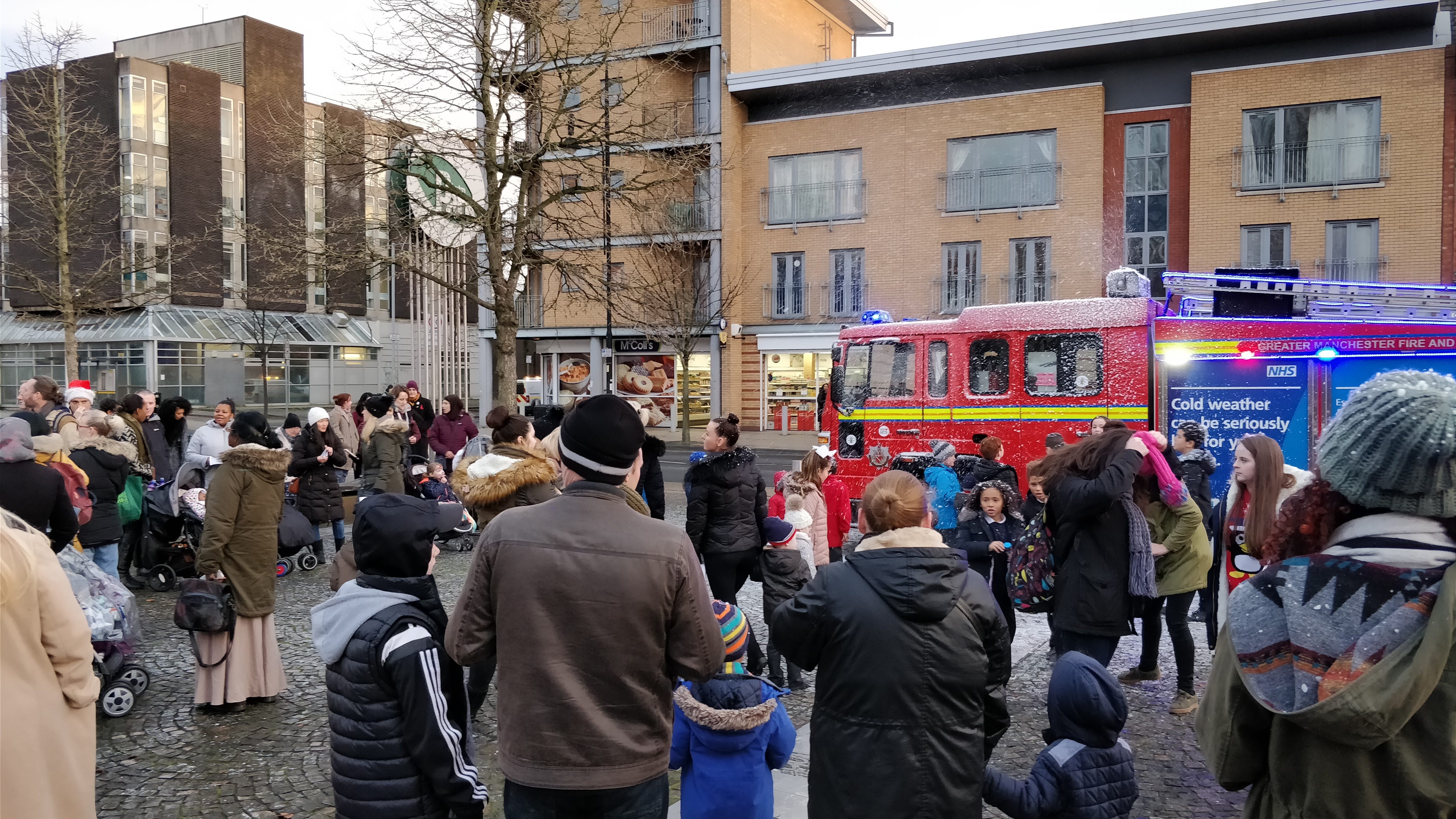 a crowd gathered outside near a fire engine with artificial snow