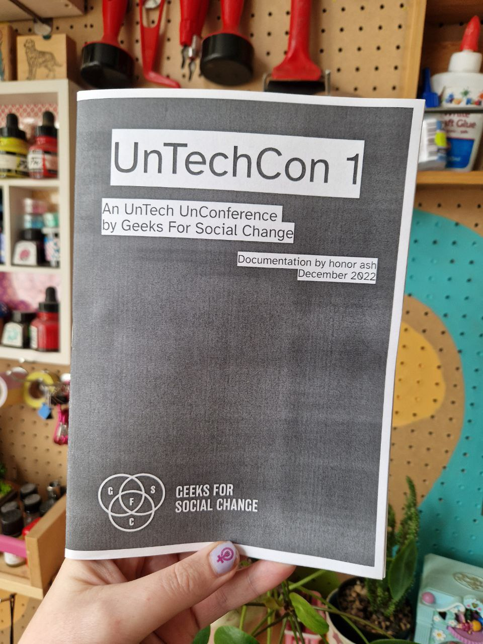 Someone with painted nails holding a photocopied version of the UnTechCon 1 documentation zine