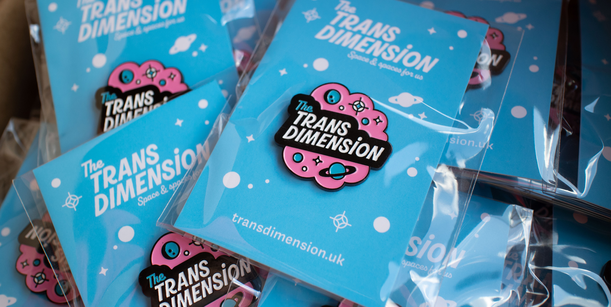 A pile of Trans Dimension enamel badges
